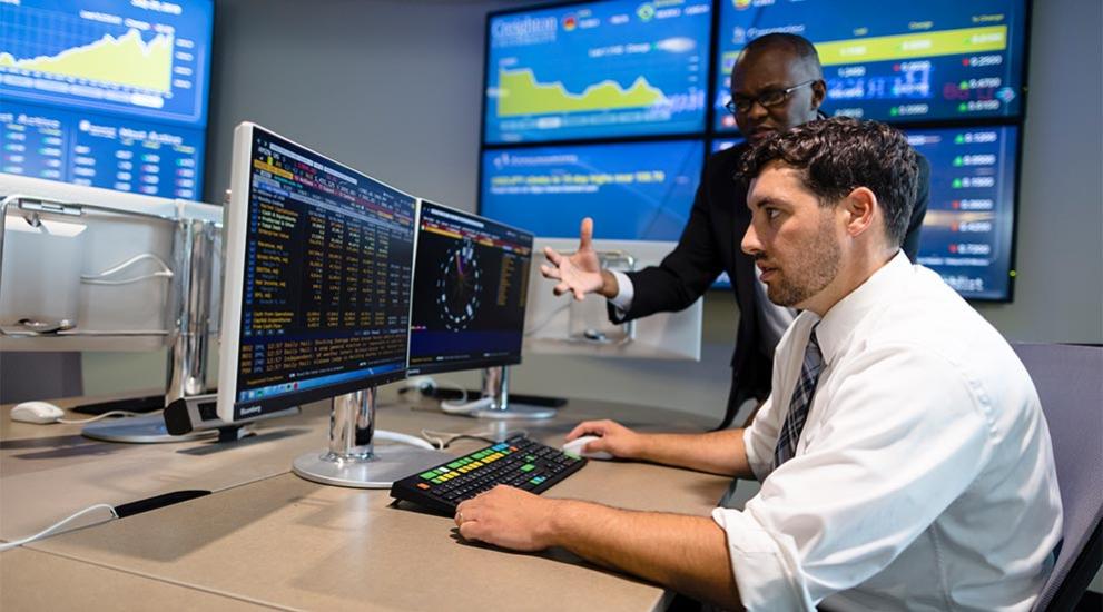 Two males at desk surrounded by stock images