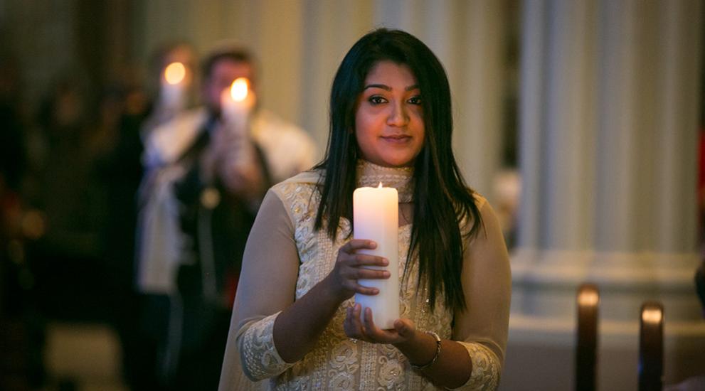 Woman holding candle in church setting.