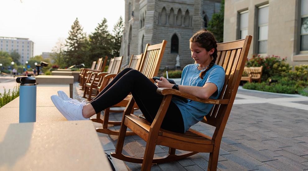 Student sitting outside in rocking chair