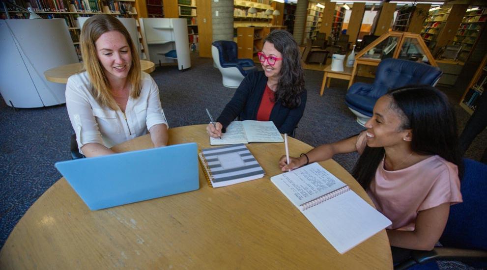 Three women at table in library