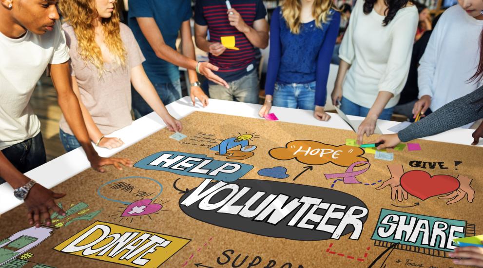 college kids making a volunteer sign