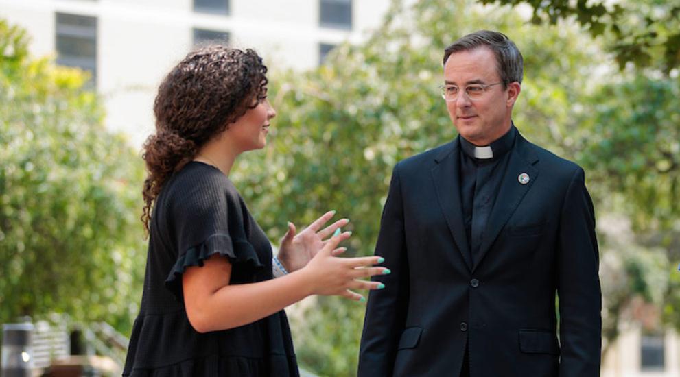 Father Hendrickson on campus with student.
