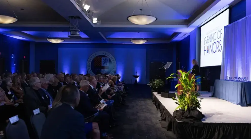 Audience in rows of chairs in front of stage. 