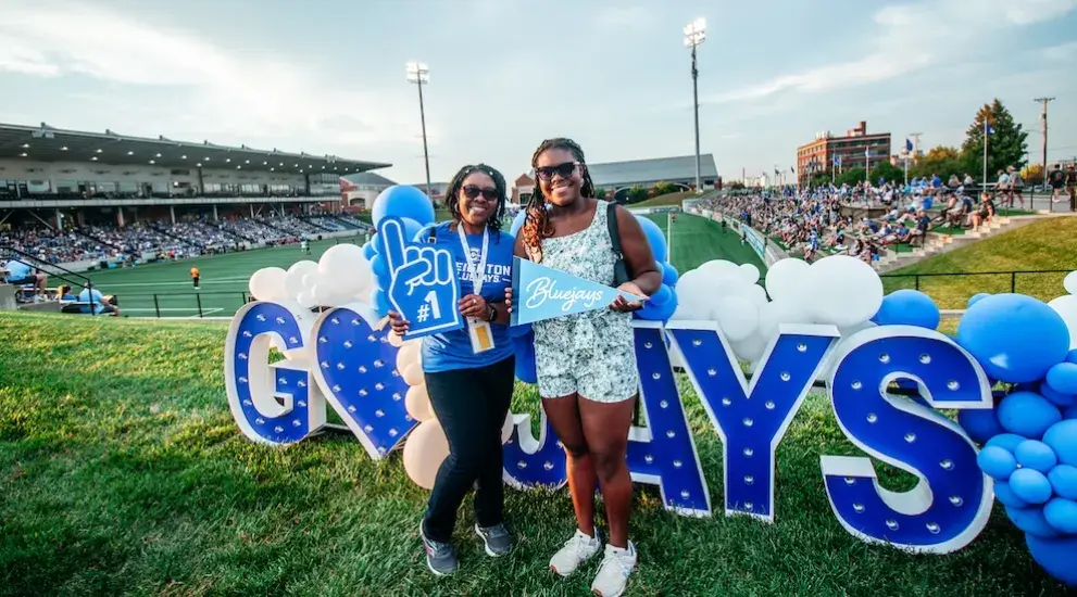 Parent and child in front of Go Jays signage.