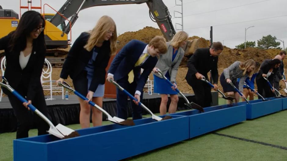 Students turning over dirt at ceremonial groundbreaking for new residence hall.