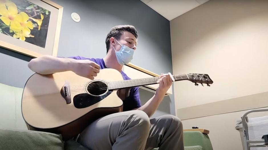 Playing acoustic guitar in hospital room.