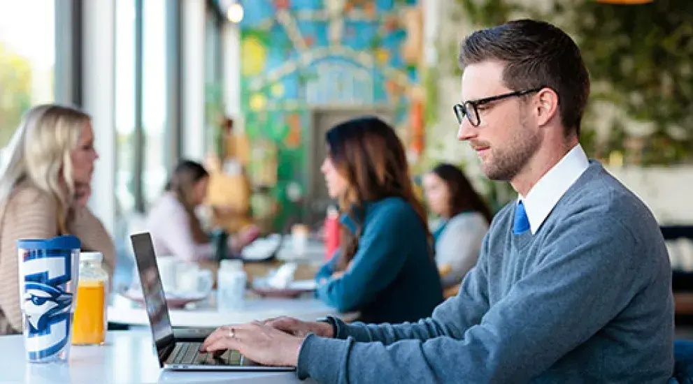 Adult student working on laptop at coffee shop